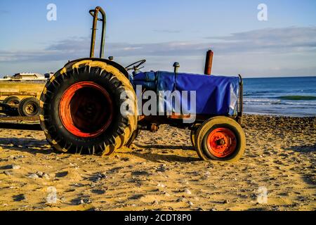 Ein rostiger alter Traktor am Cromer Strand an der North Norfolk Coast bei Sonnenaufgang. Traktoren, wie dieser, werden verwendet, um die Fischerboote zum Shorelin zu bringen Stockfoto