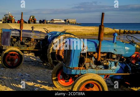 Alte und rostige landwirtschaftliche Traktoren am Cromer Strand an der Norfolk Küste bei Sonnenaufgang. Traktoren, wie dieser, werden verwendet, um die Fischerboote zu nehmen Stockfoto