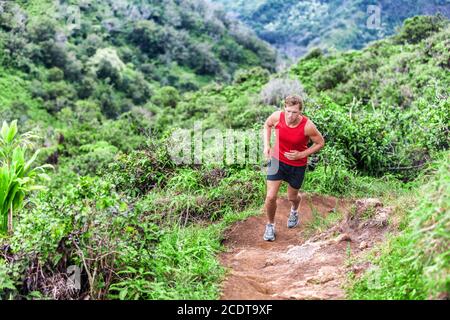 Trailrunning Mann Läufer beim Aufsteigen in Bergwald. Ultra Running Marathon in Hawaii Stockfoto