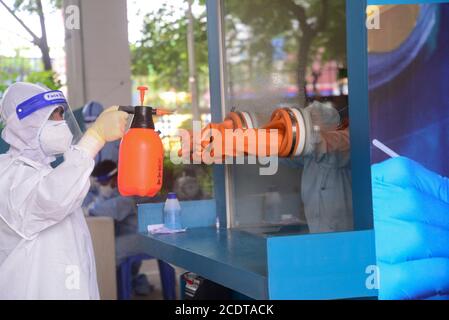 Gesundheitsfachkraft sprüht Desinfektionsmittel, nachdem ein Labortechniker eine Probe des Nasenabstrichs von einem Bewohner des Mugda Medical College and Hospital gesammelt hat. Stockfoto