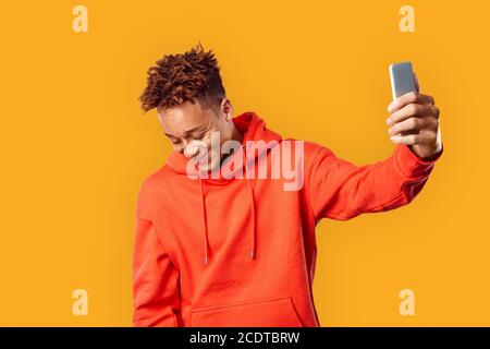 Junge Erwachsene Millennial hält Smartphone in den Händen und lächelt nett Stockfoto