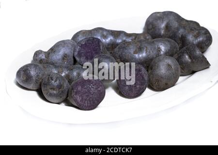 Trüffelkartoffel, Vitelotte, Blauviolette Kartoffeln auf weißem Hintergrund Stockfoto