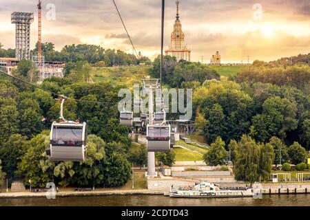 Moskau Landschaft bei Sonnenuntergang, Russland. Blick auf die Seilbahn und die Moskauer Staatliche Universität auf Sparrow Hills. Im Sommer bewegen sich die Seilbahnkabinen über den Moskwa-Fluss. Stockfoto