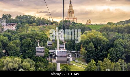 Landschaft von Moskau bei Sonnenuntergang, Russland. Panoramasicht auf die Seilbahn und die Moskauer Staatliche Universität auf den Sparrow Hills. Seilbahnkabinen bewegen sich über den Park Stockfoto