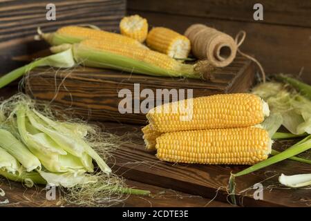 Frischer Mais am Kolben auf rustikalen Holztisch, aus der Nähe. Getönt. Geringe Tiefenschärfe. Stockfoto