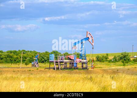 Schaukelstuhl für die Ölförderung in der trockenen Steppe an einem sonnigen Tag gegen den blauen Himmel. Industrieölförderung. Hochwertige Fotos Stockfoto
