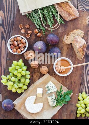 Sandwiches mit Ricotta, frischen Feigen, Prosciutto, Rosmarin und Blauschimmelkäse, Walnüssen und Honig auf rustikalem Holzbrett über schwarzem B Stockfoto