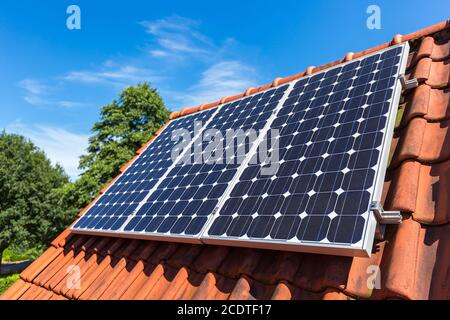 Reihe von Sonnenkollektoren auf orangefarbenem Dach Stockfoto