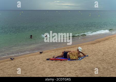 Barcelona, Spanien. August 2020. Ein einsamer Tourist liegt an einem fast menschenleeren Strand in Lloret de Mar, einer der touristischen Hochburgen der Costa Brava, Sind fast menschenleer, da die Temperaturen am letzten Augustsamstag nach der bisher kompliziertesten Saison in der Geschichte dieser Region deutlich gesunken sind, die durch die massive Abwesenheit internationaler Touristen aufgrund der Coronavirus-Krise verursacht wurde. Quelle: Matthias Oesterle/Alamy Live News Stockfoto