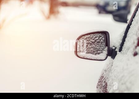 Das Auto ist mit Schnee bedeckt. Schnee auf Rückspiegel. Konzept des Fahrens im Winter mit Schnee auf der Straße. Getöntes Foto mit Stockfoto