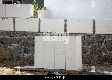 Das Porenbeton-Baumaterial liegt in der Nähe des Steinfundaments des Hauses. Stockfoto