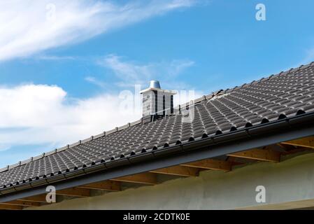 Das Dach eines Einfamilienhauses mit einer neuen Keramikfliesen in anthrazit gegen den blauen Himmel bedeckt. Vsible System Schornstein mit Fliesen bedeckt. Stockfoto