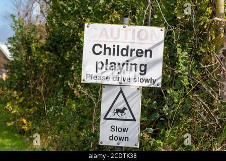 Kinder spielen, Vorsicht, bitte fahren Sie langsam, verlangsamen, Pferde, Schilder in Great Wakering, in der Nähe von Southend, Essex, Großbritannien. Ländlich, Landstraße Stockfoto