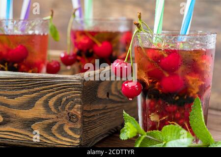 Gläser erfrischendes Getränk mit frischem Obst gewürzt und dekoriert Mit Kirschen bedeckt mit Tau-Tropfen Stockfoto