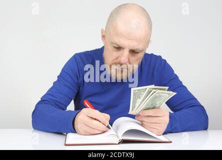 Geschäftsmann schreibt sein finanzielles Einkommen in einem Notizbuch auf Stockfoto