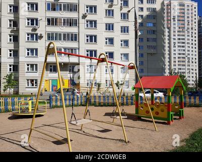 Kinderspielplatz mit Schaukeln im Hof des Wohnungsbaus in der Stadt, Russland Stockfoto