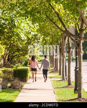 Nahaufnahme eines jungen Paares, das an einem sonnigen Sommertag in Pittsburgh, PA, USA, Hand in Hand in Hand in einem Wohngebiet im Summerset-Viertel läuft Stockfoto