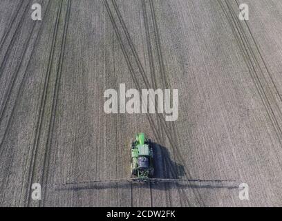 Traktor mit klappbarem System von Spritzmitteln. Düngung mit einem Traktor, in Form eines Aerosols, auf dem Feld des Winters Stockfoto