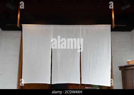 Der Vorhang-ähnliche Stoff, der vor traditionellen japanischen Restaurants und Geschäften hängt, dient nicht nur als Schild, sondern hat eine größere Bedeutung, Stockfoto