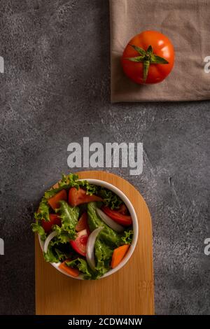 Tomaten im Salat in einer weißen Schüssel auf gräulichem Hintergrund Stockfoto