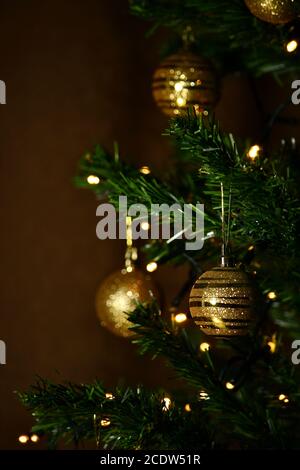 Ein goldener dekorativer Ball, der auf einem Weihnachtsbaum aufgehängt ist. Stockfoto