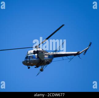 Ein Hubschrauber der landwirtschaftlichen Aviation fliegt in den blauen Himmel. Stockfoto