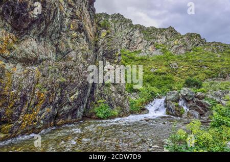 Bergbach fließt unter Klippen der Schlucht unter Felsbrocken im Altai-Gebirge, Russland Stockfoto