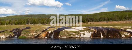 Der Firehole River mit Wasser aus den nahe gelegenen heißen Quellen, die über den Damm und in den Fluss im Yellowstone National Park, Wyoming fließen. Stockfoto