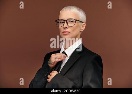 Junge elegante männliche Frau in schwarzer Jacke, weißem Hemd und Brille Stockfoto