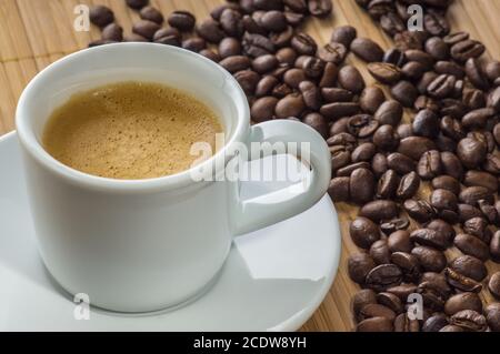 Kaffeetasse auf einer Untertasse und Körner von schwarzem Kaffee Stockfoto