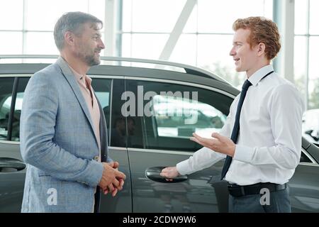 Junge selbstbewusste Vertriebsleiter Beratung reifen männlichen Kunden in Auto Zentrieren Stockfoto