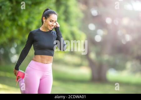 Junge Läuferin, die sich vor dem Laufen aufwärmt und Musik hört. Stockfoto