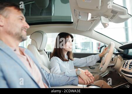 Ziemlich junge weibliche Klientin der Auto-Mitte hält durch Steer Während der Probefahrt Stockfoto