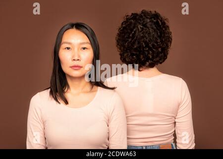 Junge ernsthafte Brünette Frau der asiatischen Ethnie stehen vor Der Kamera Stockfoto