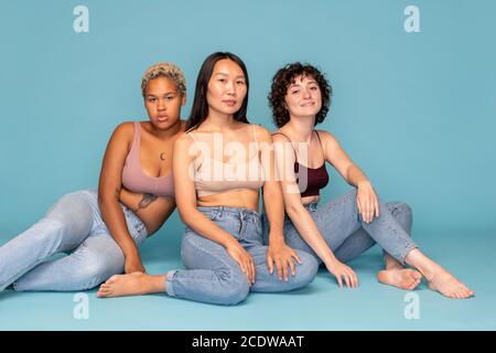 Drei junge, zeitgenössische Frauen asiatischer, kaukasischer und afrikanischer Ethnien Stockfoto