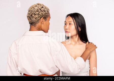 Junge ernsthafte asiatische Frau mit dunklen langen Haaren Blick auf Afrikanisches Weibchen Stockfoto