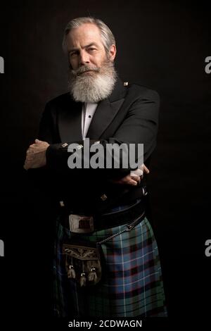 Reifes männliches Modell mit Kilt mit grauer Frisur und Bart Stockfoto