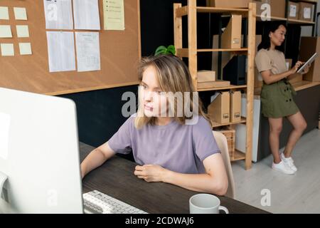 Zwei moderne junge Arbeiterinnen im Lagerraum, die online gehen Aufträge Stockfoto