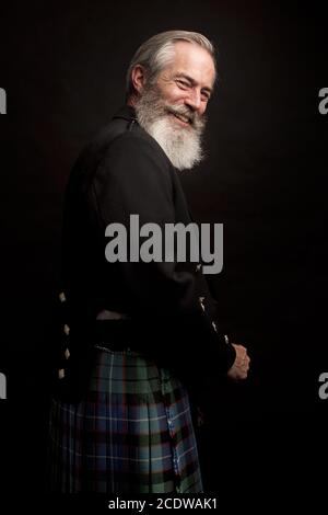 Reifes männliches Modell mit Kilt mit grauer Frisur und Bart Stockfoto