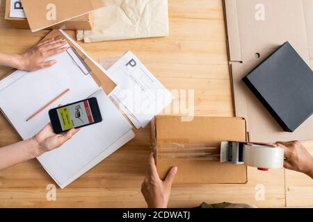 Draufsicht der weiblichen Hände halten Smartphone mit Seite von Online-Shop Stockfoto