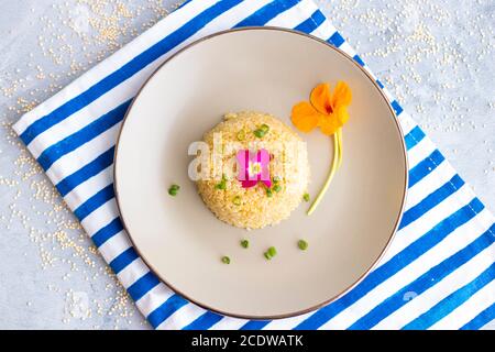 Quinoa-Teller-Präsentation mit essbaren Blumen dekoriert Stockfoto