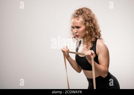 Junge Sportlerin mit blondem lockiges Haar, die sich beim Training bemüht Stockfoto