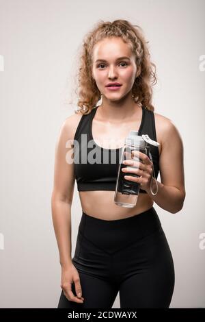 Junge fröhlich fit Frau in schwarz Trainingsanzug hält Plastikflasche Von Wasser Stockfoto