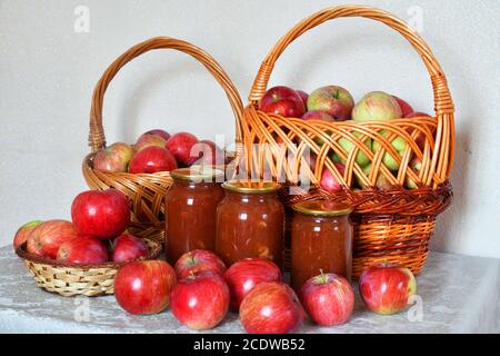 apfelmarmelade und frische Äpfel in einem Weidenkorb Stockfoto