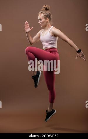 Aktive Frau in Sportbekleidung Biegen linkes Bein im Knie und Rechter Arm im Ellbogen Stockfoto