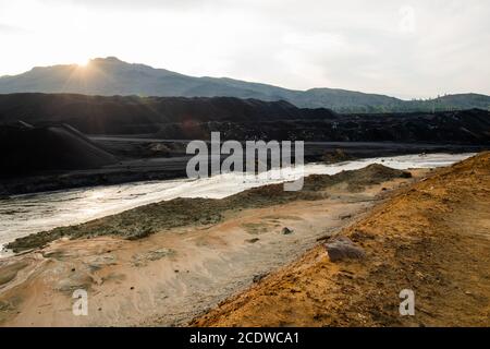 Landschaft des verlassenen Territoriums mit schmutzigem Wasser im Fluss und Verschmutzter Boden Stockfoto
