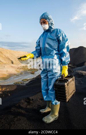 Junge Ökologin in schützender Arbeitskleidung mit Aktenkoffer mit Proben Stockfoto