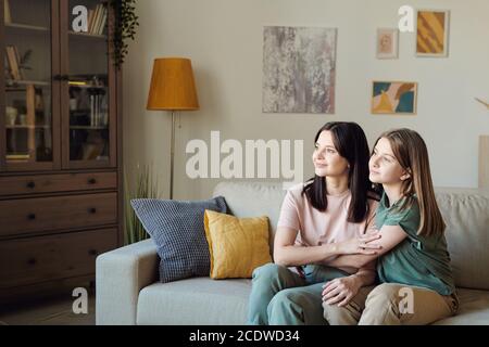 Zwei junge erholsame Frauen, Mutter und Tochter, die durch ein großes Fenster blicken Stockfoto