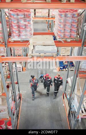 Drei interkulturelle Lagerarbeiter in Uniform diskutieren Arbeitsfragen Stockfoto