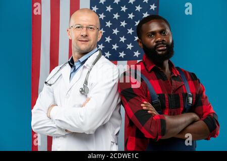 Reifer glatzköpfiger Arzt und junger afrikanischer Reparaturmann, der die Arme kreuzt Brust Stockfoto